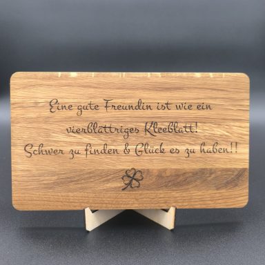 Holzscheibe mit eingraviertem Text über Freundschaft und Glück.