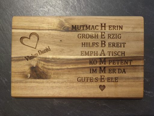 Holzbrett mit eingravierten Worten und Herzen in verschnörkelter Schrift.