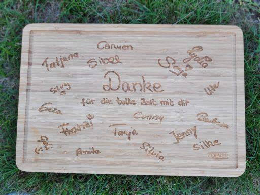 Holzbrett mit dem Wort "Danke" und mehreren eingravierten Namen.